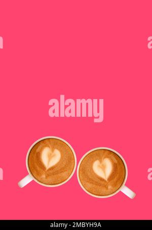 Zwei Cappuccino-Kaffees mit herzförmigem Latte Art auf rosafarbenem Hintergrund Stockfoto