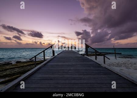 Ein goldener Sonnenuntergang über dem Strand mit einer Promenade Stockfoto