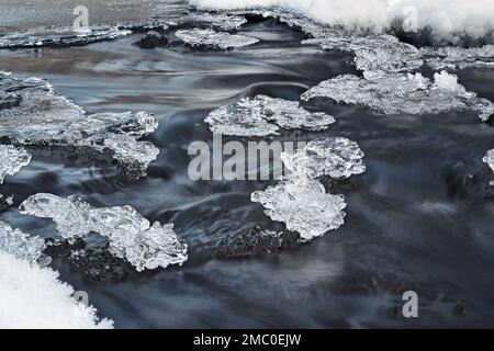 Eis auf dem gefrorenen Fluss, Nahaufnahme Makrodetails, Wasser fließt unter, Langzeitaufnahme Foto Stockfoto