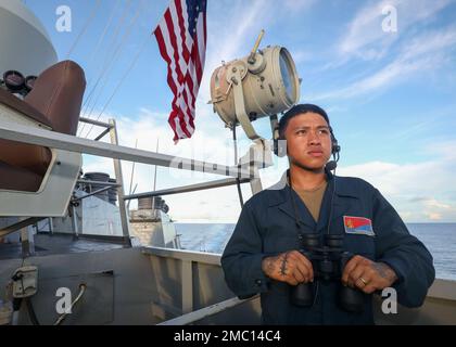 PHILIPPINE SEA (23. Juni 2022) Seemann Filmer Joshua Baco aus Raleigh, North Carolina, beobachtet das Brückenspiel an Bord der Arleigh-Burke-Klasse-Guided-Missile Destroyer USS Benfold (DDG 65). Benfold ist dem Kommandeur, der Task Force (CTF) 71/Destroyer Squadron (DESRON) 15, der größten nach vorn eingesetzten DESRON der Marine und der Hauptstreitkräfte der US-7.-Flotte zugewiesen. Stockfoto