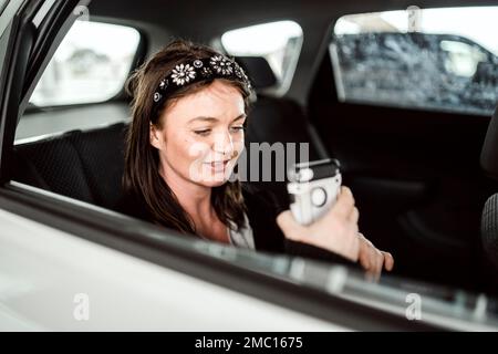 Ein Taxi oder ein Uber-Passagier, der über das Telefon auf dem Rücksitz des Autos spricht Stockfoto