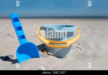 Nahaufnahme von Spielzeugeimer und Spaten am Sandstrand gegen Meer und blauen Himmel Stockfoto