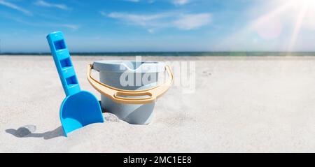 Nahaufnahme von Spielzeugeimer und Spaten am Sandstrand gegen Meer und blauen Himmel Stockfoto