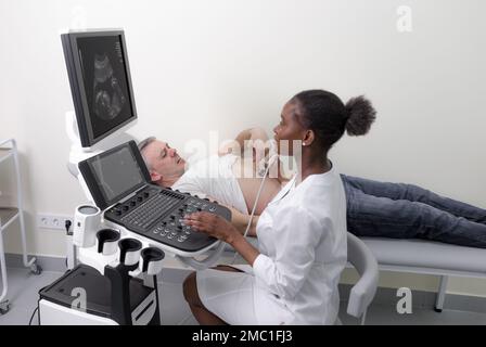 Eine afroamerikanische Ärztin führt eine Ultraschalluntersuchung eines Patienten mit starken Schmerzen durch Stockfoto