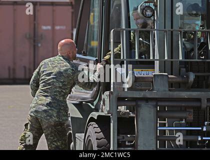 Ben Wallace, Verkehrstechniker beim 2 Air Movement Squadron, Canadian Forces Base Trenton, schüttelt sich nach der Gabelstapleraufgabe 10k während des Port Dawg Rodeo auf der Joint Base Lewis-McChord, Washington, am 23. Juni 2022 mit einem Teamkollegen die Hand. Vierzehn Teams von Port dawgs aus der ganzen Welt nahmen an fünf Veranstaltungen Teil, um die Ehre von Top Dawg zu erlangen: Ein Palettenbauförderwettbewerb, ein 10k-km-Kurs zum Umgang mit Gabelstaplern, ein 25K-km-Laderflugzeug-Upload, eine Herausforderung für die KampfFitness und ein Wissenstest zum Zentrum für Gleichgewicht. Stockfoto