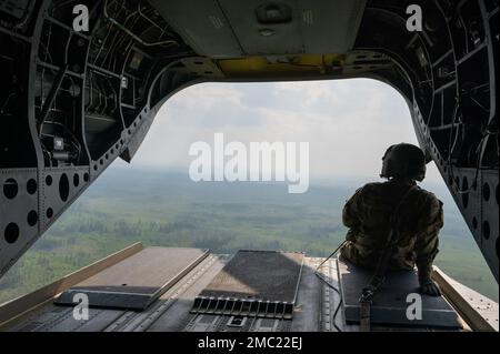 EIN US-AMERIKANISCHER Soldat der Armee sitzt auf der Rampe eines CH-47 Chinook, der der B-Kompanie ‚Sugar Bears‘ 1-52. Luftbataillon, 16. Kampfluftfahrtbrigade zugeteilt wurde, während eines Fluges von der Clear Space Force Station, Alaska, zum Luftwaffenstützpunkt Eielson, Alaska, Zur Unterstützung der Zivilführertour der Abteilung der Luftwaffe, veranstaltet von Joint Base Elmendorf-Richardson, Alaska, 23. Juni 2022. Clear SFS dient als Heimat für Arktis-Flugzeuge und Wächter, die den 13. und 213. Weltraumwarngeschwadern zugeteilt sind, und bietet 24/7 Raketenwarnung, Raketenabwehr und Weltraumbereichserkennung. Stockfoto