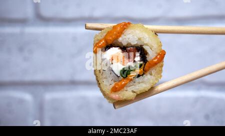 Sushi-Rolle mit Essstäbchen auf Backsteinwänden Stockfoto