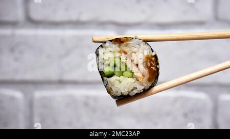 Zwei Essstäbchen, die ein Stück Sushi holen Stockfoto
