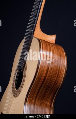 Klassische Gitarrenspitze isoliert auf schwarzem Hintergrund mit einer wunderschönen Mosaikrosette, Blick von der Oberseite. Wunderschönes brasilianisches Holz - Pau Ferro Stockfoto