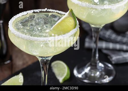Margarita-Cocktail mit Eis, Limette und Salzwand auf einem schwarzen Schieferbrett Stockfoto