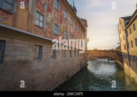 Seitenansicht des Alten Rathauses mit Fresken und Brücke über den Regnitz bei Sonnenuntergang - Bamberg, Bayern, Deutschland Stockfoto