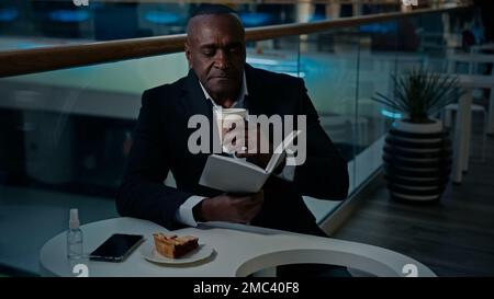 Afroamerikanischer Arbeiter Geschäftsmann Unternehmer sitzt am Tisch in der Cafeteria Restaurant Trinken aromatischen Kaffee trinken Tee Latte Cappuccino Stockfoto