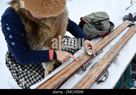 Bayern, Deutschland. 21. Januar 2023. 21. Januar 2023, Bayern, Krün: Ein Teilnehmer wachst seine Holzskier mit einer Kerze vor dem „Nostalski“-Skirennen im Barmsee-Lift. Mit alten Holzskiern und Schnürsenkel aus Leder, zumindest aus dem vergangenen Jahrhundert, beginnen die Teilnehmer mit einem lustigen Rennen. Foto: Angelika Warmuth/dpa Credit: dpa Picture Alliance/Alamy Live News Stockfoto