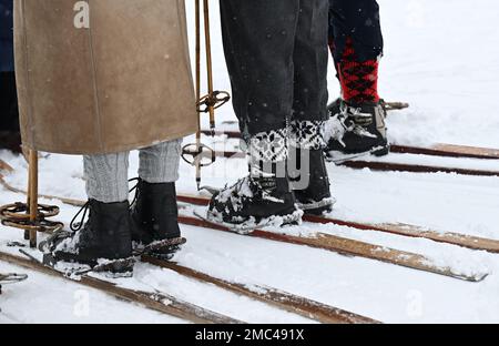 Bayern, Deutschland. 21. Januar 2023. 21. Januar 2023, Bayern, Krün: Teilnehmer mit ihren Holzskiern warten auf den Beginn des Skirennens „Nostalski“ am Barmsee Lift. Mit alten Holzskiern und Schnürsenkel aus Leder, zumindest aus dem letzten Jahrhundert, beginnen die Teilnehmer mit einem lustigen Rennen. Foto: Angelika Warmuth/dpa Credit: dpa Picture Alliance/Alamy Live News Stockfoto