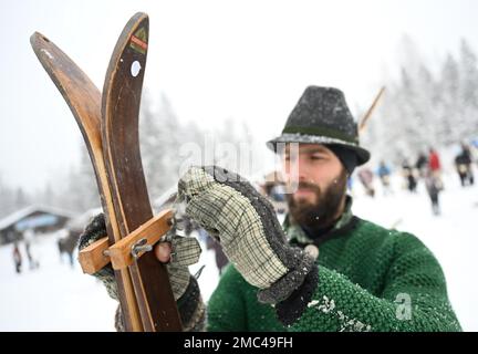 Bayern, Deutschland. 21. Januar 2023. 21. Januar 2023, Bayern, Krün: Ein Teilnehmer öffnet den Besitzer auf seinen Holzskiern vor dem „Nostalski“-Skirennen im Barmsee-Lift. Mit alten Holzskiern und Schnürsenkel aus Leder, zumindest aus dem vergangenen Jahrhundert, beginnen die Teilnehmer mit einem lustigen Rennen. Foto: Angelika Warmuth/dpa Credit: dpa Picture Alliance/Alamy Live News Stockfoto