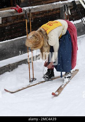 Bayern, Deutschland. 21. Januar 2023. 21. Januar 2023, Bayern, Krün: Eine Teilnehmerin schnallt sich vor dem „Nostalski“-Skirennen im Barmsee-Lift auf ihren Holzskiern an. Mit alten Holzskiern und Schnürsenkel aus Leder, zumindest aus dem vergangenen Jahrhundert, beginnen die Teilnehmer mit einem lustigen Rennen. Foto: Angelika Warmuth/dpa Credit: dpa Picture Alliance/Alamy Live News Stockfoto
