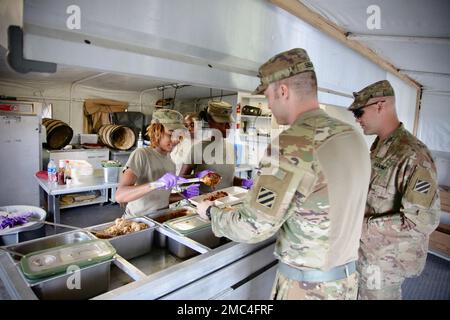 Soldaten der Georgia Army National Guard, die dem 148. Brigaden-Stützbataillon zugeteilt sind, servieren am 24. Juni 2022 während der jährlichen Ausbildung in Fort Stewart, Georgia, ein Dinner für andere Soldaten Stockfoto