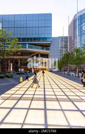 Beleuchteter Gehweg über einem platz, der vom Tokyo International Forum zum Mitsuo Aida Museum führt, während der Blue Hour am Nachmittag. Stockfoto