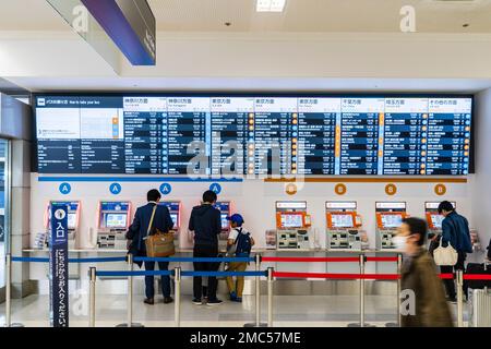 Tokio Haneda International Airport. Terminal 1 Interieur. Menschen mit einer Reihe von Bus Ticket Maschinen A und B, mit beleuchtetem Zeitplan vor. Stockfoto