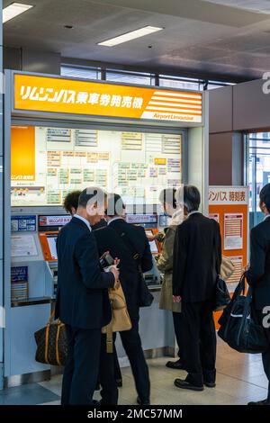 Internationaler Flughafen Tokio Haneda. Terminal eins innen. Japanische Angestellte nutzen den Automaten der Airport Limousine, um Tickets zu kaufen. Stockfoto