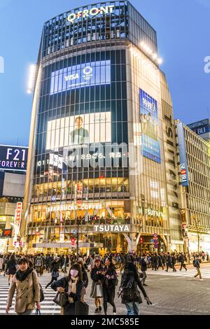 Tokio. Shibuya. Die berühmteste Sehenswürdigkeit jagt Kreuzung, mit Überqueren der Straße vor Starbucks. Blaue Stunde am Abend, Gebäude beleuchtet Stockfoto