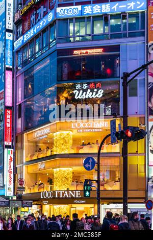 Tokio, Shibuya, Abend. Gäste sitzen im L'Occitane Cafe und im Ushi 8 Restaurant oben. Vordergrund, Ampel und Schild für Shibuya Station, Tokio Stockfoto