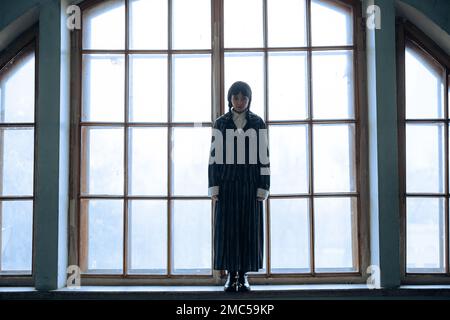 Dnipro, Ukraine - 30. Dezember 2022: Cosplayer Girl im Bild von Wednesday Addams aus der gleichnamigen Comedy Horror-Serie 'Wednesday' Posen im Saal gegen Stockfoto