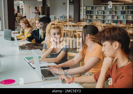 Fokussierte Klassenkameraden, die Netbooks in der Bibliothek verwenden, während sie recherchieren Stockfoto