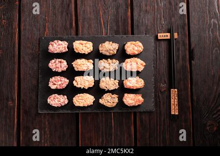 Set aus Gunkan Maki Sushi mit verschiedenen Arten von Fischlachs, Jakobsmuscheln, Barsch, Aal, Garnelen und Kaviar auf Holztisch-Hintergrund. Sushi-Menü. Japanisch Stockfoto