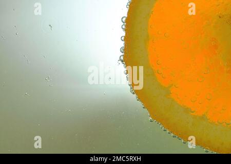 Scheibe Orangenfrucht in Wasser auf weißem Hintergrund. Orangefarbene Nahaufnahme in Flüssigkeit mit Blasen. Eine Scheibe rote, reife Orange im Wasser. Makrobild von Obst in Stockfoto