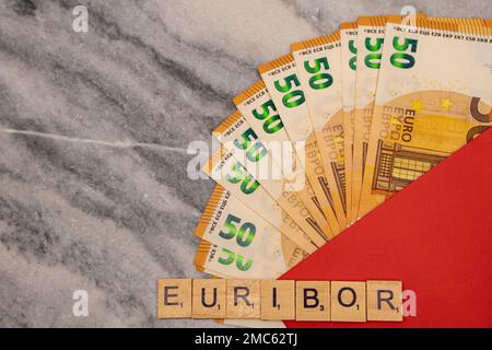 Word EURIBOR ist in Holzbuchstaben geschrieben, in der Nähe von 50 Euro-Banknoten und rotem Umschlag. Stockfoto