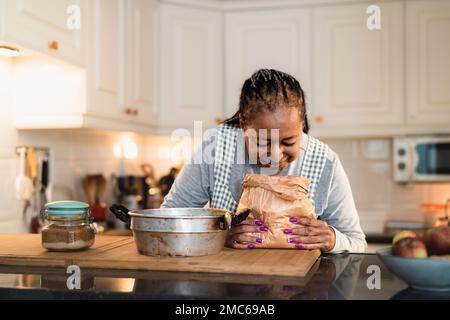 Glückliche ältere afrikanische Frau, die ein selbstgemachtes Dessert zubereitet Stockfoto