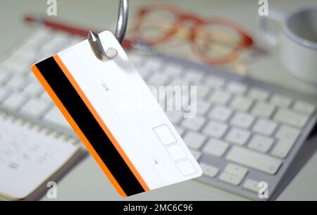 Daten-Phishing, großer Haken mit Kreditkarte auf der Computertastatur und Arbeitsplatz verschwommen im Hintergrund Stockfoto