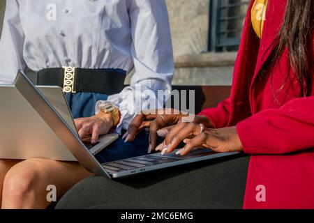 Nahaufnahme von zwei Geschäftsfrauen, die mit ihren Laptops im Freien tippen. Digitales Nomadenkonzept Stockfoto