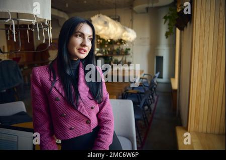Porträt einer selbstbewussten kaukasischen Geschäftsfrau mittleren Alters in elegantem Anzug im modernen Restaurant-Interieur. Wirtschaft, Finanzen und Beschäftigung, weibliche Succ Stockfoto