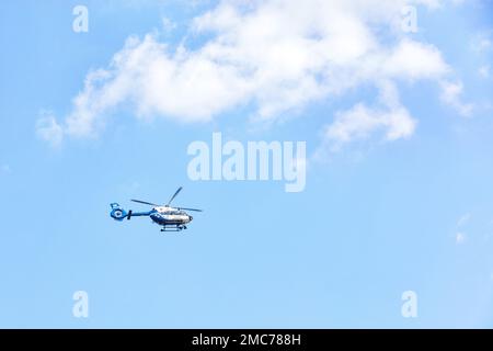 Ein Hubschrauber der Nationalpolizei der Ukraine fliegt an einem sonnigen Tag im Profil gegen einen Himmel mit weißen Wolken. Stockfoto