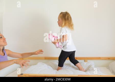 Das kleine Mädchen rennt zu den Armen seiner Mutter und hält sie fest und liebevoll in der Hand Stockfoto
