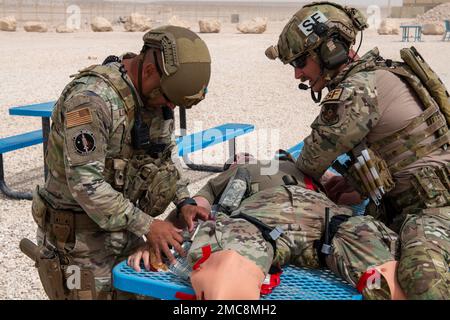 USA Air Force Tech. Sergeant Edward Lopez und U.S. Air Force Tech. Sgt. Johnathan Finer, 379. Geschwader der Expeditionstruppen, erste Hilfe für ein Opfer einer simulierten Explosion während einer Übung auf dem Al Udeid Luftwaffenstützpunkt, Katar, 27. Juni 2022. Das simulierte Opfer hatte massive Blutungen aus beiden Beinen. Stockfoto