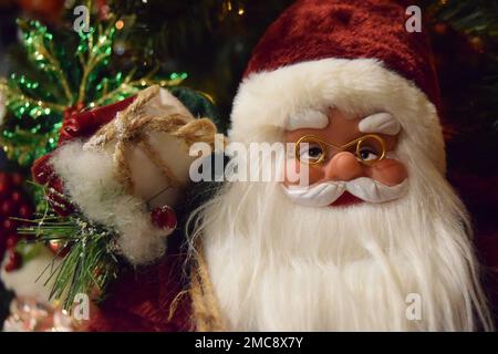 Ein festlicher Weihnachtsmann in einem traditionellen rot-weißen Hut mit einem großen Sack voller Geschenke, verpackt in Papier und Schnur. Stockfoto