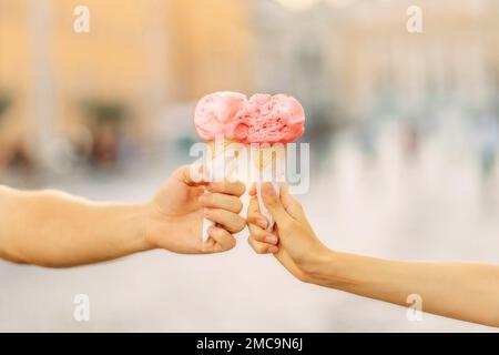 Männer- und Frauenhände halten helle Eiskrem. Hände halten Eiskrem. Sommerzeit. Touristenunterhaltung Stockfoto