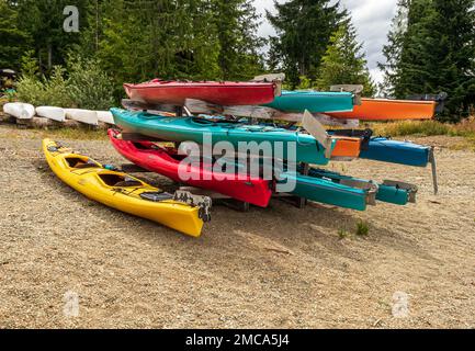 Farbenfrohe Kajaks, die auf den Sommer warten, am Strand von Strathcona Lake, B.C. Stockfoto