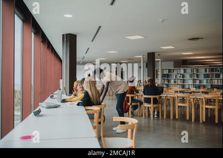Inhalte für verschiedene Gruppen, die sich unterhalten und Netbooks in der Bibliothek verwenden Stockfoto