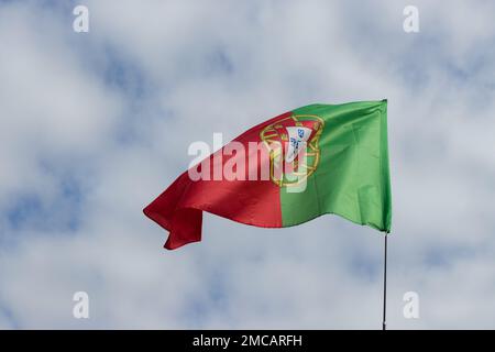 Die sich entwickelnde portugiesische Flagge am blauen Himmel. Fahne Nahaufnahme bei klarem Wetter. Platz für Text. Stockfoto