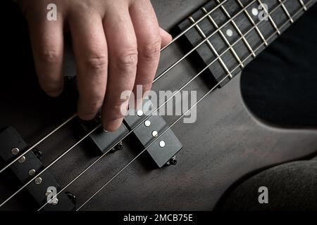 Bass Gitarrenspieler Hand-Nahaufnahme, Lern- und Übungsthema. Rockmusik auf der elektrischen Bassgitarre, Livemusik und Können. Naher Blick auf Gitaris Stockfoto