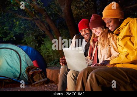 Freunde, die am Winterabend zusammen beim Camping Computer benutzen. Stockfoto