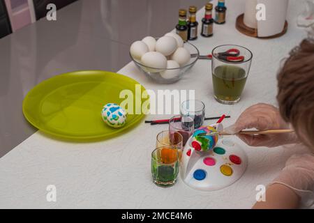 Nahaufnahme von Kinderhänden in Handschuhen zum Malen von Eiern zu Ostern. Schweden. Stockfoto