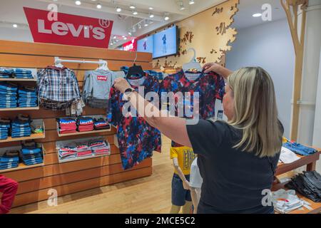 Frau wählt T-Shirt in der Kinderabteilung für Macy's Supermarkt. New York. USA. Stockfoto