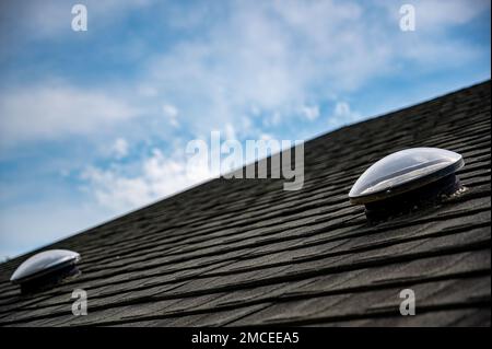 Kuppelförmiges Sonnenröhren-Oberlicht auf Asphalt-Schindeldach Stockfoto