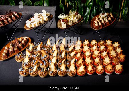 Viele kleine Gläser mit Mousse mit Blaubeeren und Keksen am Buffet Stockfoto