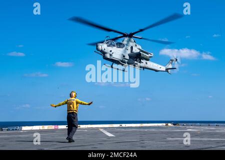 NORDPAZIFIK (19. Januar 2023) - Aviation Boatswain’s Mate 3. Class Derrick Koch, aus Pine Plains, N. Y., dem Amphibienschiff USS Green Bay (LPD 20) zugewiesen, signalisiert einem AH-1Z Cobra Helikopter der Marine Medium Tiltrotor Squadron (VMM) 262, auf dem Cockpit des Schiffes zu landen. Green Bay ist im Einsatzgebiet der 7. Flotte tätig. 7. Fleet sind die USA Die größte Flotte der Navy, die mit einer Anzahl von Flotten ausgestattet ist, und arbeitet regelmäßig mit Alliierten und Partnern zusammen, um eine freie und offene Region im Indo-Pazifik zu erhalten. (USA Navy Foto von Mass Communication Specialist 2. CLA Stockfoto